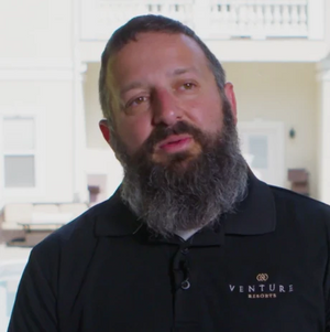 Man with graying beard and wearing a dark button up shirt